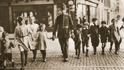 Un poliziotto in servizio che aiuta i bambini ad attraversare la strada alla fine della giornata scolastica, da Wonderful London, pubblicato 1926-27 da English Photographer